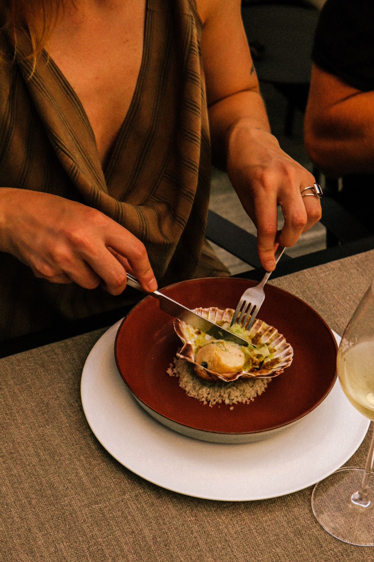 Guest enjoying a scallop dish with a glass of white wine at Maison Parole