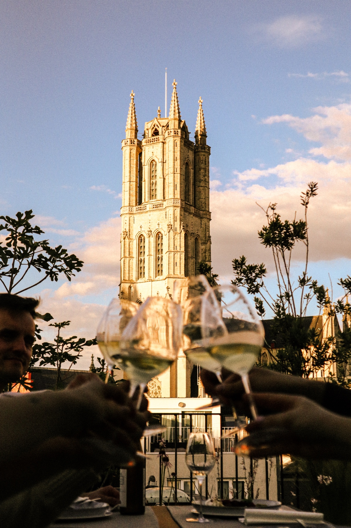 Guests toasting with white wine on the terrace with view of the Ghent belfry